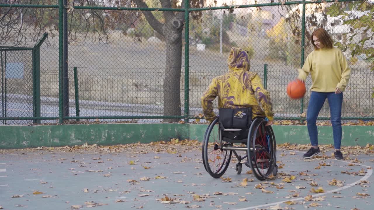 un joven en silla de ruedas jugando al baloncesto en cámara lenta.