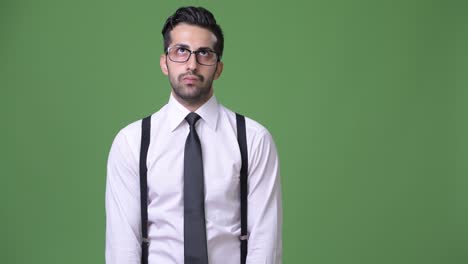 joven empresario persa barbudo y guapo contra un fondo verde