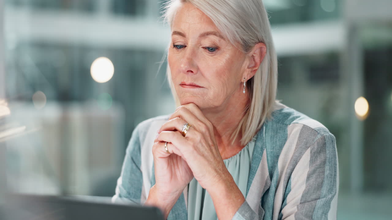 A mature woman thoughtfully contemplates a work problem in her office