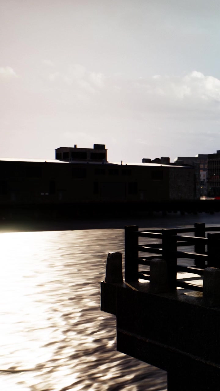 Sunset over the water with buildings and a pier in the background