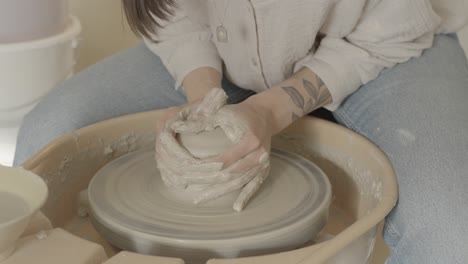 a female potter centering clay on the wheel