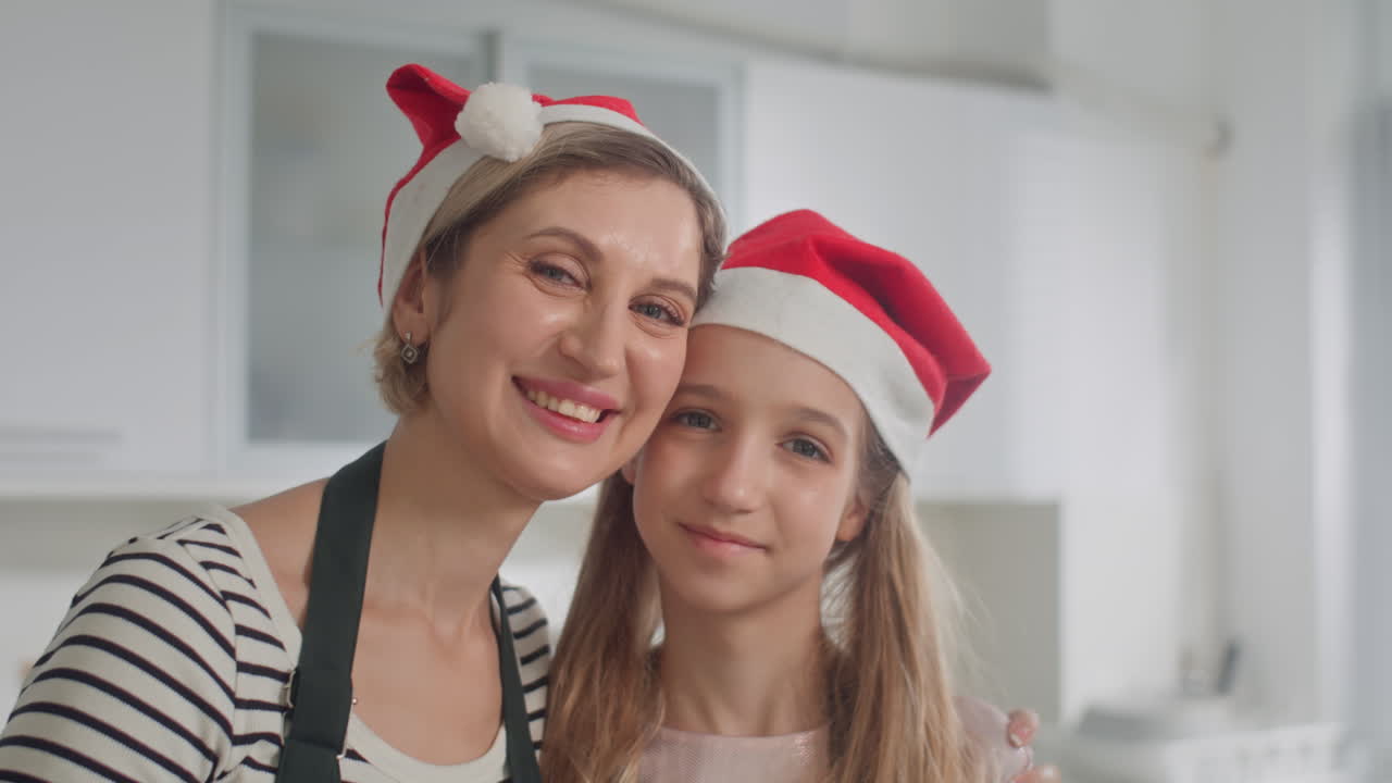 Portrait of Cheerful Mother and Daughter in Christmas Hats Cooking at Home