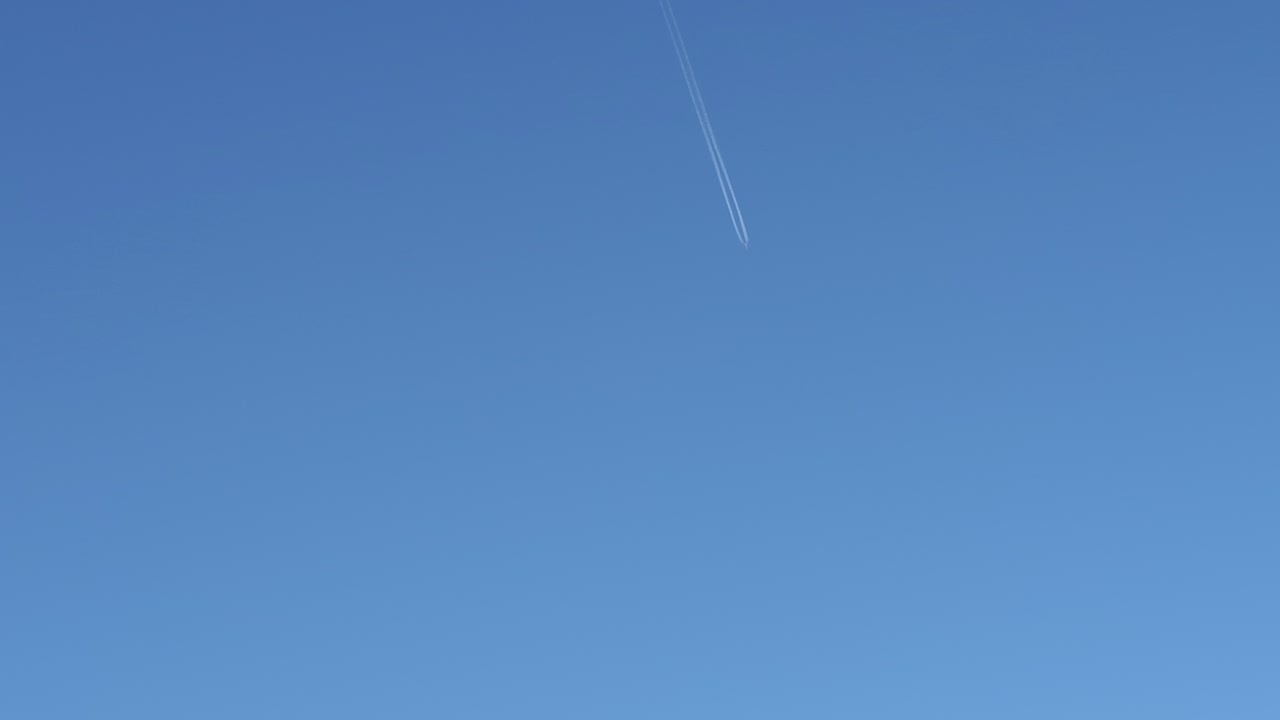 흰 연기의 흔적을 남기고 탁 트인 구름 없는 하늘에서 멀리 있는 비행기