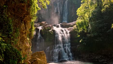 a spectacular aerial view captures the majestic multi-tiered nauyaca waterfall bathed in the soft, golden light of sunrise, nestled within costa rica's pristine tropical rainforest