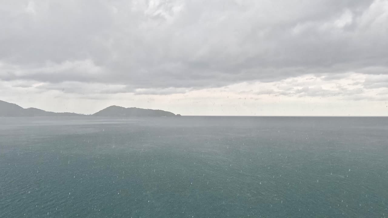 Drone camera glides over calm tropical sea toward distant islands, moody overcast lighting, wide shot