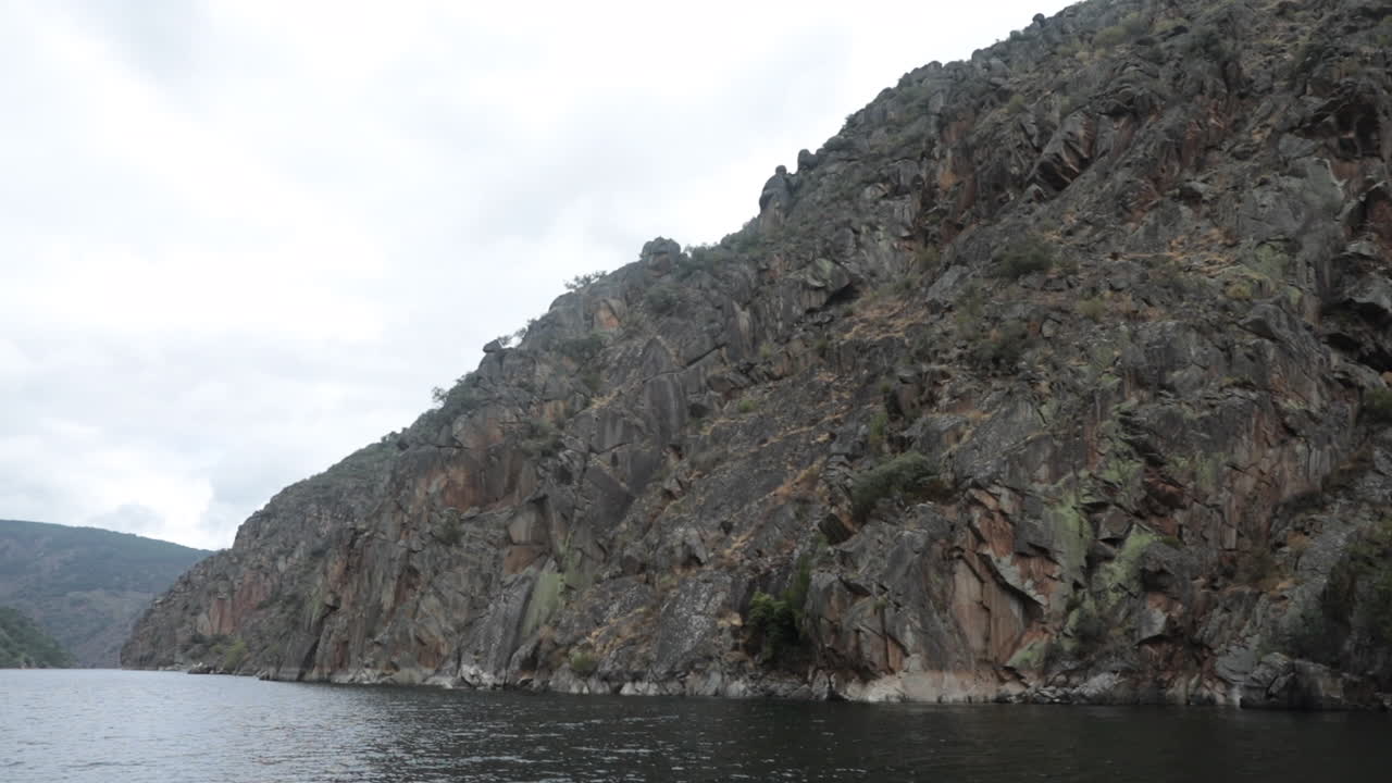 가파른 바위 절벽은 구름이 많은 날에 평온한 물 위로 올라와 거친 자연 풍경을 만니다.