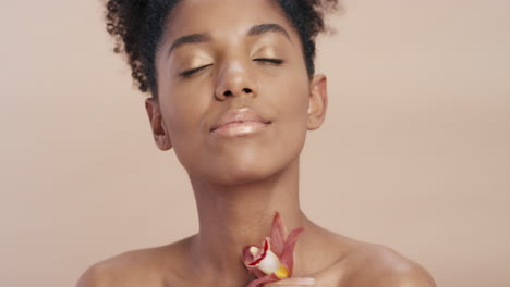 Cerrar-Retrato-De-Belleza-Hermosa-Mujer-Afroamericana-Tocando-El-Cuerpo-Con-Flor-De-Orquídea-Acariciando-Una-Tez-De-Piel-Saludable-Disfrutando-De-Una-Suave-Fragancia-De-Esencia-Natural-Concepto-De-Cuidado-De-La-Piel