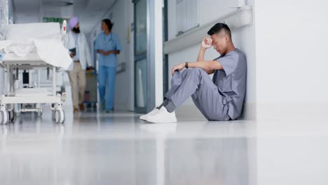 Stressed-asian-male-surgeon-sitting-and-leaning-on-wall-in-hospital-in-slow-motion