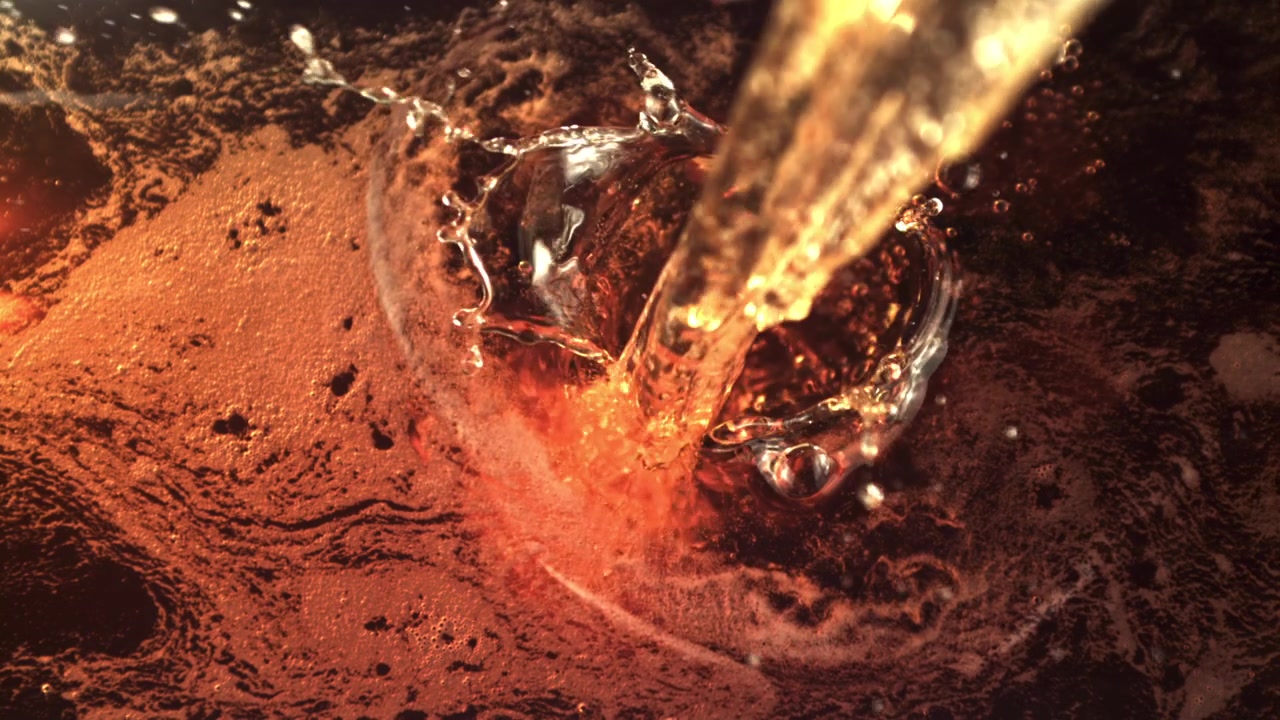 Versamento al rallentatore di liquido ambrato scuro con bolle e schiuma