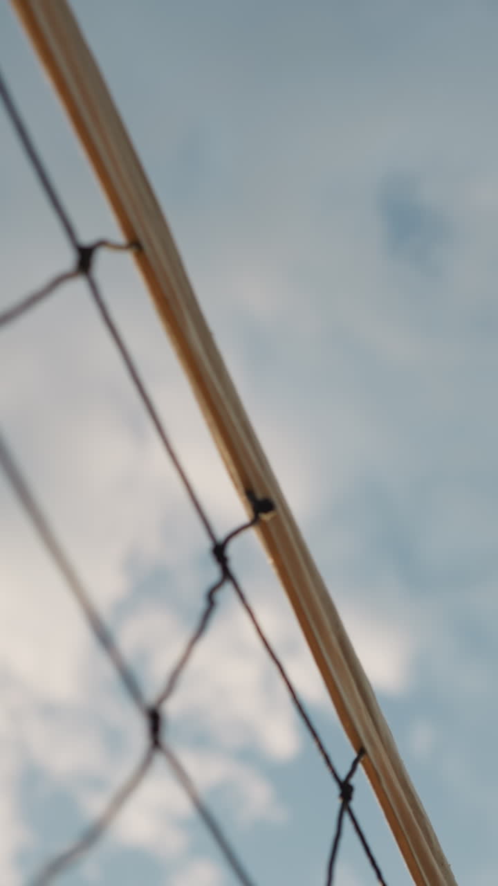 primer plano de la red de voleibol con voleibol jugando sobre ella, bajo el cielo abierto, se ve la pelota pasando sobre la red con un fondo de cielo nublado
