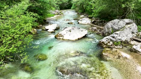 Drones-Aéreos-Vuelan-Lentamente-Sobre-El-Flujo-De-Agua-Turquesa-Entre-Un-Frondoso-Bosque-En-El-Valle-De-Logar,-Viajes-Y-Turismo-En-Eslovenia