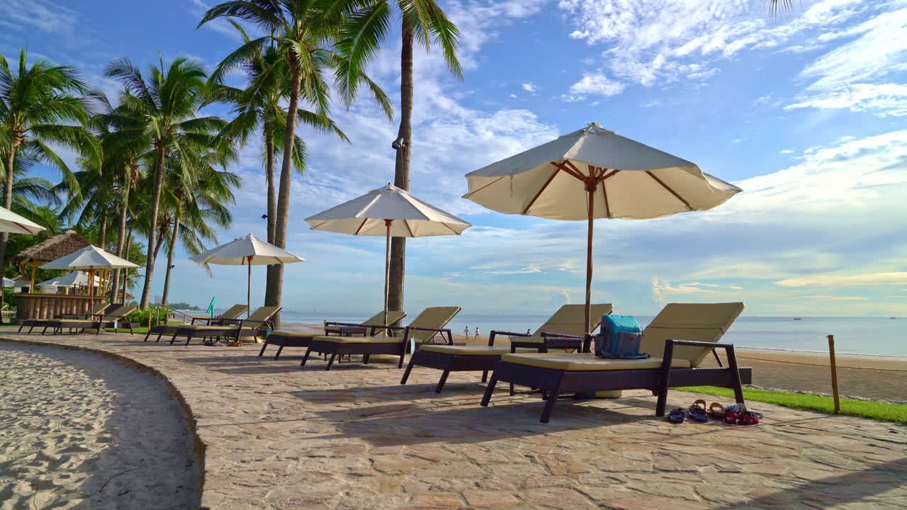 일몰 또는 일출 하늘에 코코넛 야자수가 있는 호텔 및 리조트의 야외 수영장 주변에 있는 아름다운 고급 우산과 의자 - 휴일 및 휴가 개념