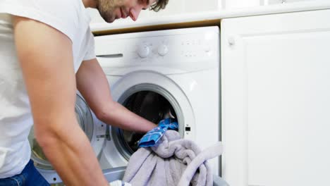 man putting dirty clothes into washing machine