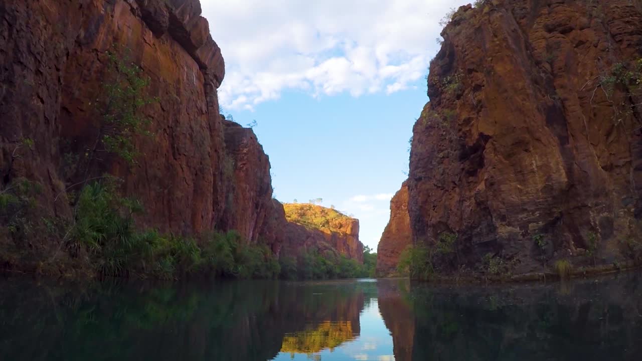 imágenes de una canoa de un profundo desfiladero con paredes de roca roja y agua suave y reflectante