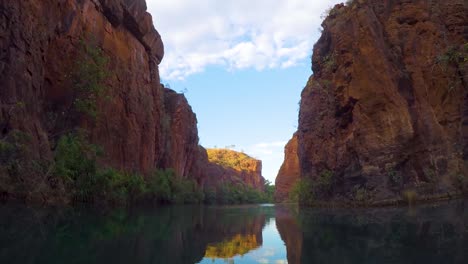 footage from a canoe of a deep gorge with red rock walls and smooth reflective water