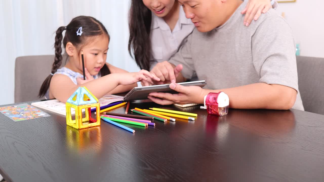 Parents guide young daughter using tablet for creative drawing in bright, cozy living room