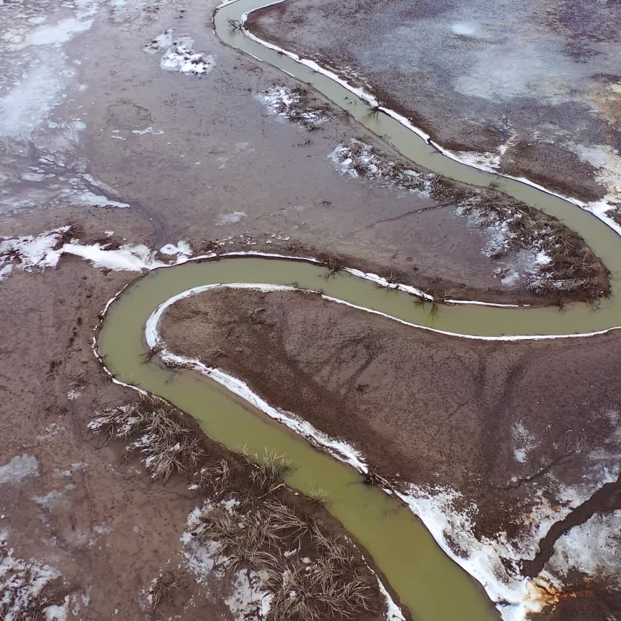 Muddy background. Dirty narrow stream of dried river. Ecological disaster. Natural problems in the world. Muddy water in tortuous river. Top aerial view