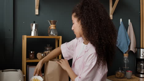 woman unpacks food delivery in her kitchen
