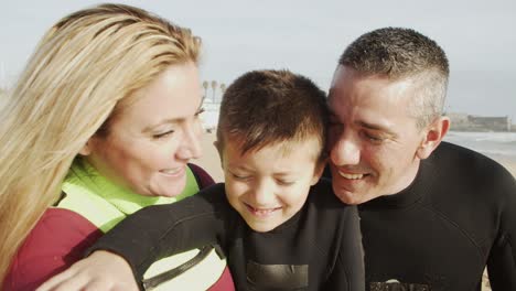 happy family in wetsuits smiling at camera