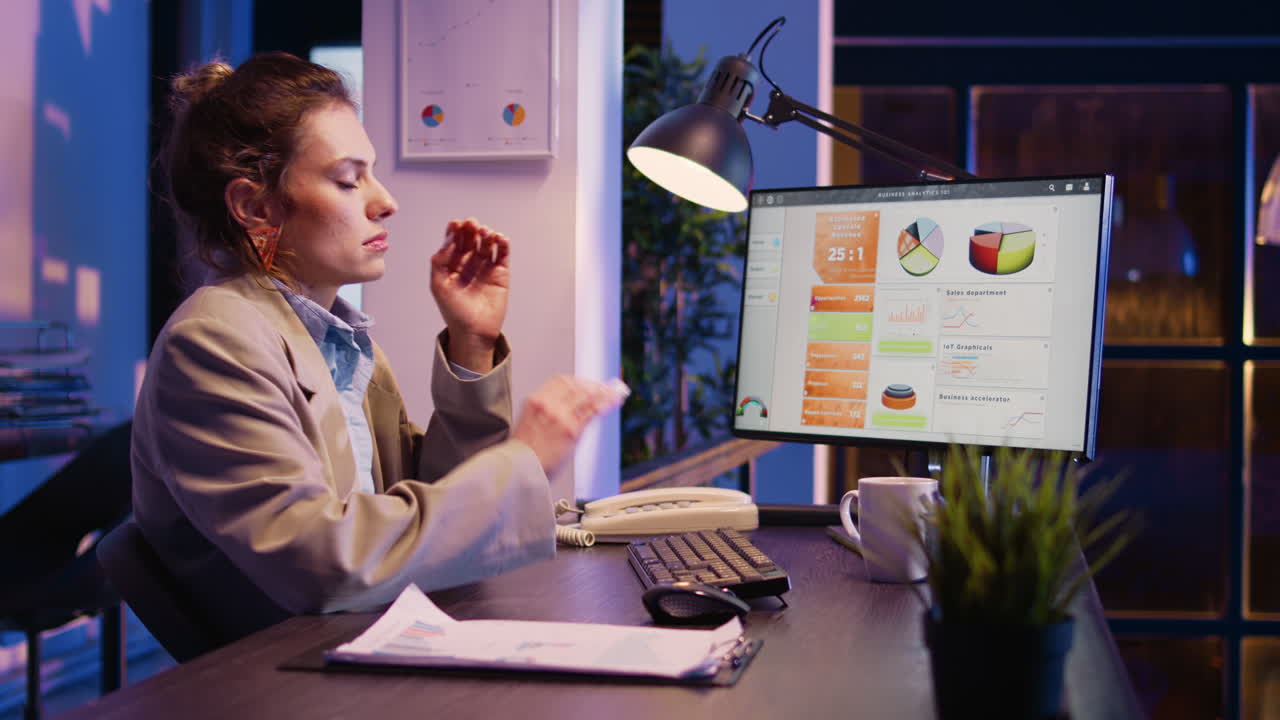 Businesswoman working late at night analyzing data on a computer