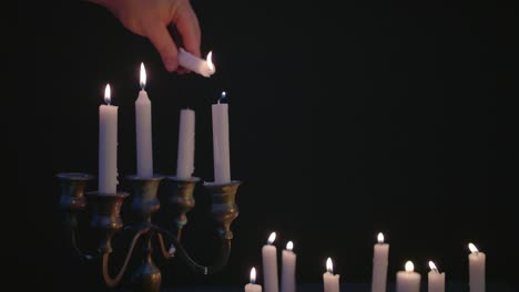 a white candle lights a few candles on a candelabra with a group of white candles lit up and running for a while in slow motion