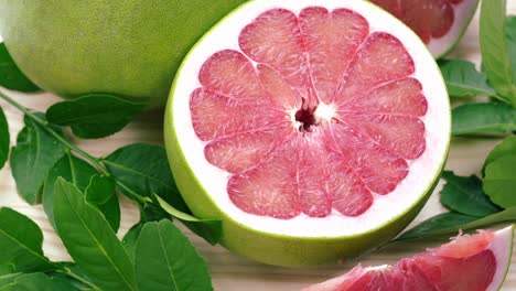 top view rotate red pomelo fruit with leaves on wooden table in garden, red pomelo fruit with leaves in wooden background 4k resolution.