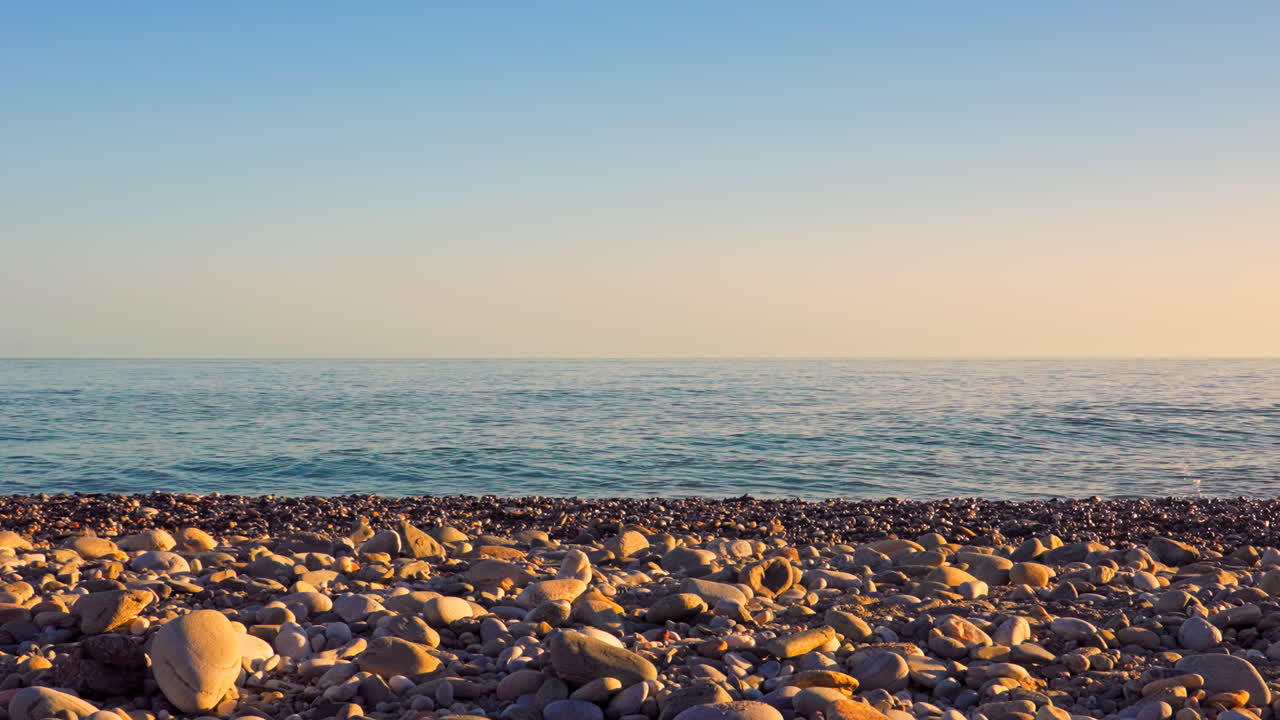 해가 지는 동안 은 하늘과 함께 바위 해변에 평온한 바다 파도