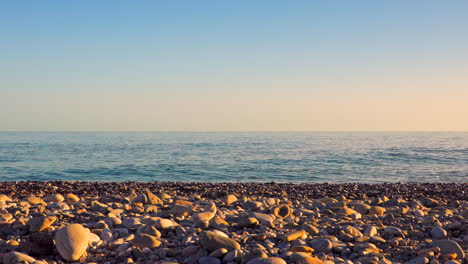 calm ocean waves on a rocky beach with clear sky during sunset