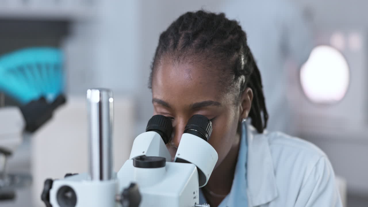 Black woman, scientist with microscope to analyze