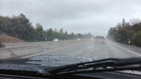 A-truck-drives-through-a-rainstorm-on-the-highway-as-the-windshield-wipers-keep-the-visibility-clear-through-the-windshield