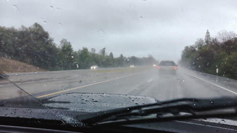 a truck drives through a rainstorm on the highway as the windshield wipers keep the visibility clear through the windshield