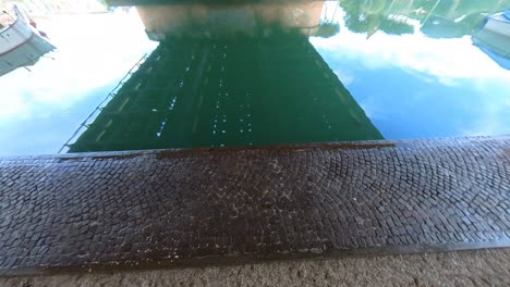 reflective canal water with cobblestone dock