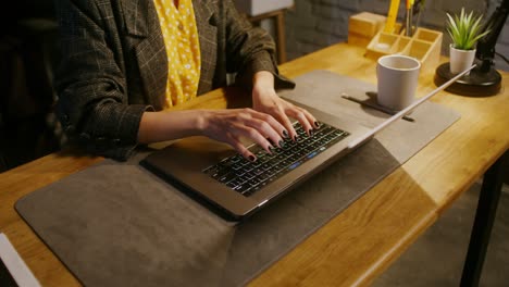 mujer escribiendo en una computadora portátil en un escritorio de la oficina en casa