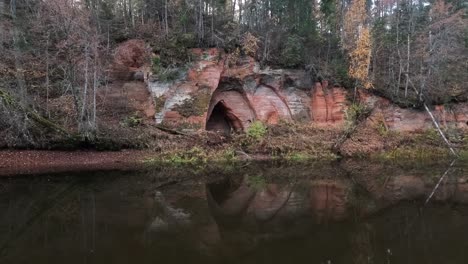 angels cave, a red sandstone cliff in a shape of angel wings, at the river salaca in skanaiskalns nature park in mazsalaca, latvia, autumn time