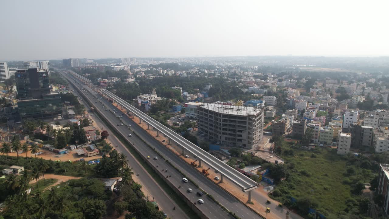 Video udara menunjukkan jalan layanan, mobil yang melaju kencang, serta bangunan perumahan dan komersial di jalan tol India yang sedang berkembang pesat.