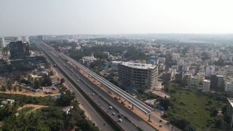 an aerial video shows a service road, fast-moving automobiles, and residential and commercial buildings on an indian highway that is expanding quickly