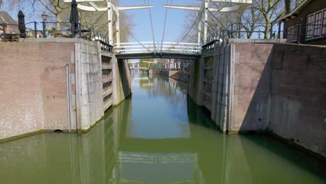 Aerial-view-flying-under-foot-bridge-on-Dutch-canal