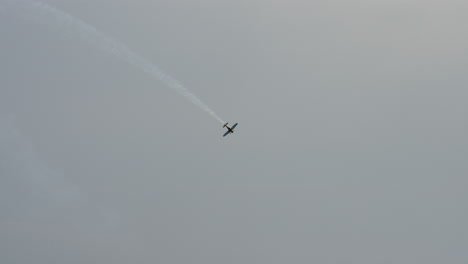 aerobatic aircraft flies straight up into the sky leaving white smoke trail behind