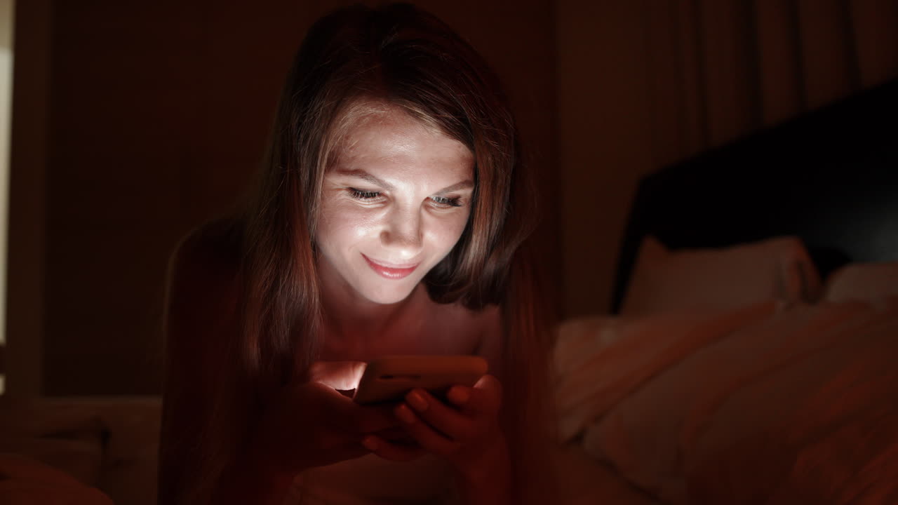 Woman using phone in bed at night