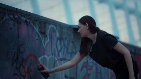 Girl-painting-graffiti-on-urban-street.-Woman-using-spray-bottle-for-graffiti