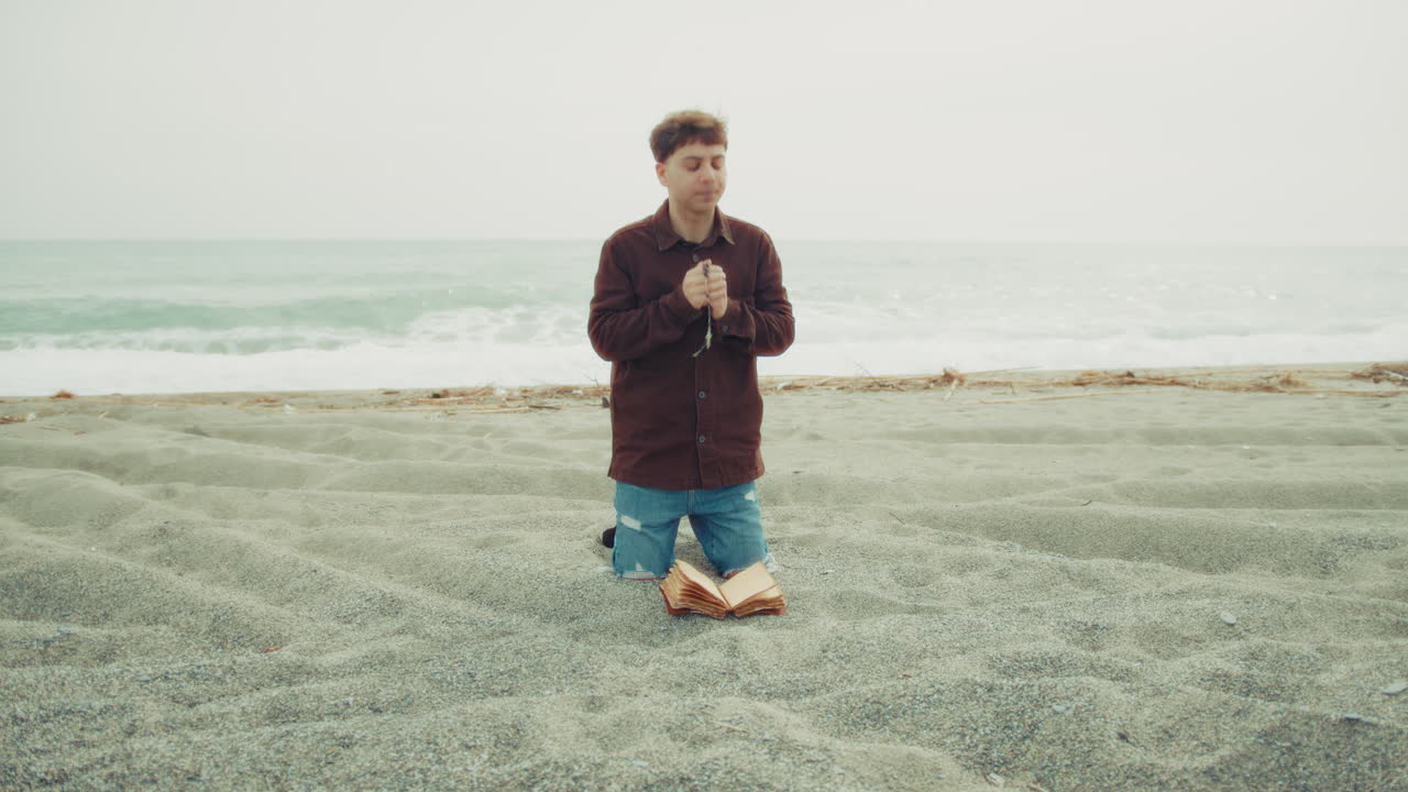 Man Praying With Passion On The Beach With The Bible Book