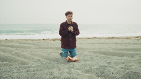 man praying with passion on the beach with the bible book