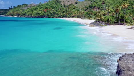 Aerial-forward-tilt-up-over-picturesque-exotic-sand-beach-surrounded-by-palms