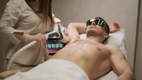 a man undergoing a laser hair removal treatment on his chest with a professional technician in a clinic