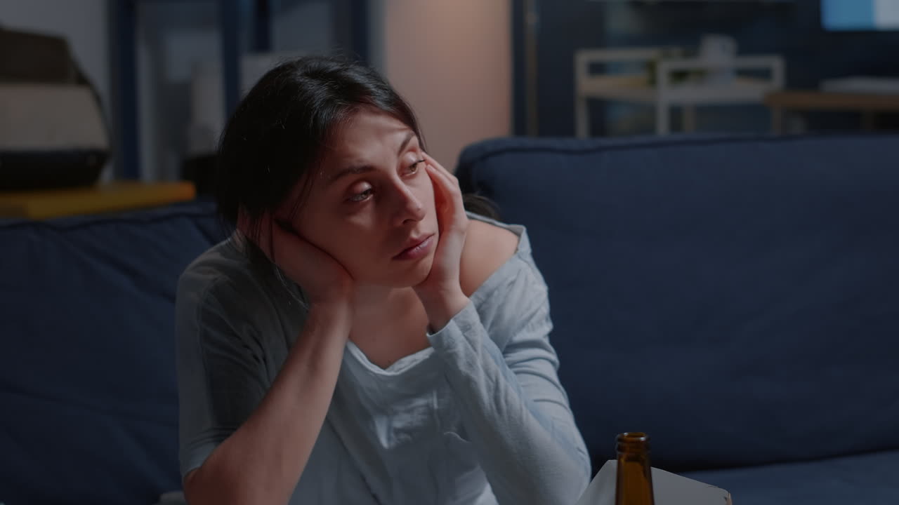 Lonely unhappy, depressed, frustrated woman sitting on couch with head on hends feeling disappointed, suffering from insomnia