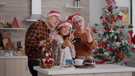 granddaughter taking selfie using smarphone with grandparents during christmas holiday celebration