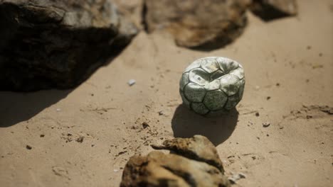 vieja pelota de fútbol en la playa de arena