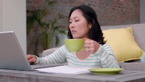 Woman-drinking-coffee-while-typing-on-laptop