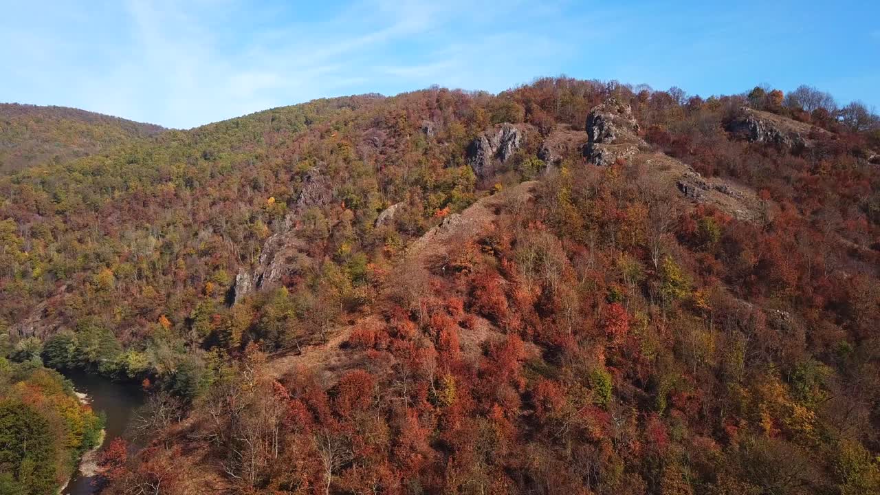 toma aérea de un río que fluye rodeado de montañas cubiertas de árboles de otoño