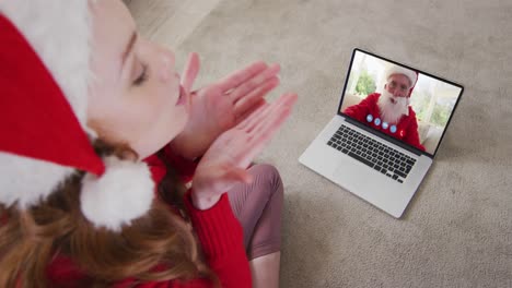 mujer caucásica con sombrero de papá noel en una videochat portátil durante la navidad en casa